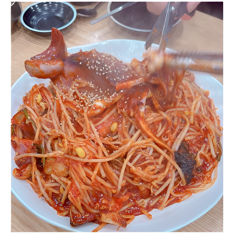 매콤한 소스에 비벼진 해산물과 면 요리가 담긴 접시