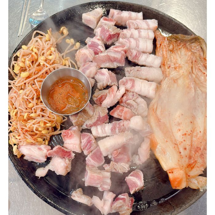 구운 삼겹살, 숙주나물, 그리고 고추장이 담긴 그릇이 있는 철판 요리